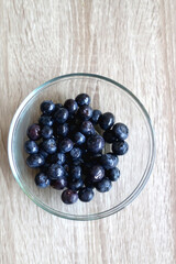 Bowl of blueberries on wooden table.