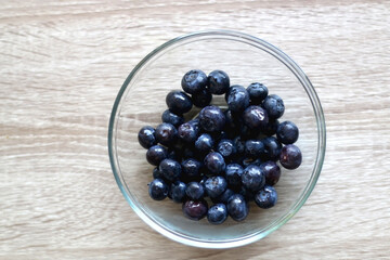 Bowl of blueberries on wooden table.