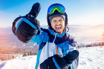 Smiling skier man and takes selfie photo in winter ski resort, sunny and bright sky