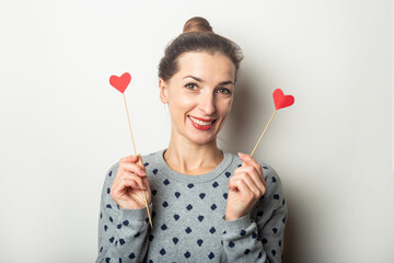 Young woman holding hearts on sticks on a light background. Valentine's day, birthday. Banner