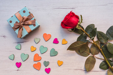 Romantic background with red rose on wooden table, gift with bow, top view, copy space