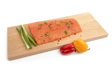 filet of salmon on a cedar plank with green onions and sweet peppers isolated on white