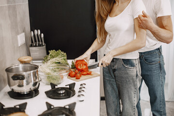 Cute couple at home. Lady in a white t-shirt. People prepare a salad.