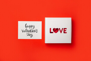 Gift box with text Love and card on a red background. Composition Valentine's Day. Banner. Flat lay, top view