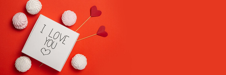 Gift box with the text Love, sweets and hearts on a stick on a red background. Composition...
