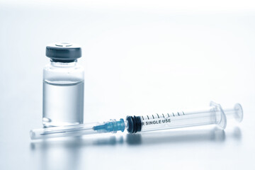 Medical syringe with a needle and a bollte with vaccine.