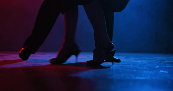 Silhouette of tango dancers feet in a dark room with blue and red spotlight. Close-up beautiful movements of the legs in dance, tango. 4k, ProRes