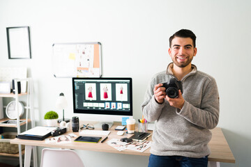 Portrait of a happy photographer holding a camera at his office
