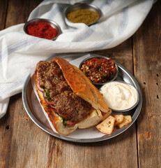meatball sandwich with mezes on a metal plate on wooden background
