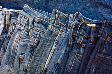 Stack of old blue jeans as a background.Denim fabric closeup.
