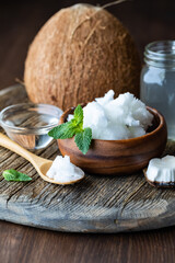 Coconut oil on a wooden board with a coconut in behind.