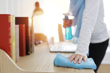 Close up active young beautiful asian muslim housewife woman hands in sleepwear cleaning up wooden table with computer. Portrait girl with happy emotional cleaning bedroom new apartment after moved in