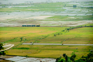 Landscape of wet lands with a train passing by in the middle captured high angle.