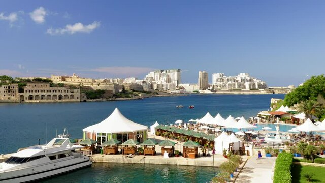 Malta habour drone shot over hotel pool area and out over open water. 

Blue sky, summer time. 

4k 25FPS 10bit DLOG-REC709