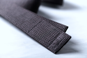 Black karate belt on rustic wooden background. Close up. 
