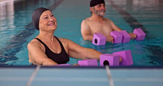 Senior woman exercising arms with dumbbells in aerobics class