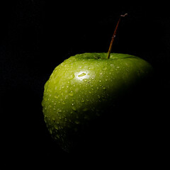 Green apple with drops on black background