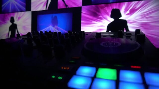 dj video audio controller flashing presents with multiple screens playing shadow silhouette dancers layered ontop of camera pointing the nightclub dance floor as modern vdj flaunts the party loop rave