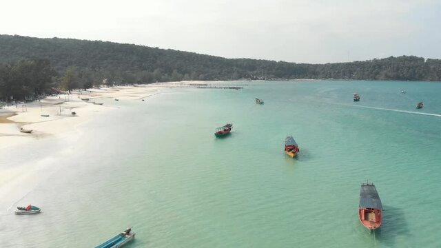 Shoreline circling around shallow bay with fisher boats moored in Saracen Bay in Koh Rong Sanloem, Cambodia - Aerial  Panoramic shot