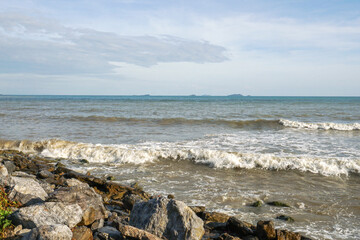 Fototapeta na wymiar The windy waves hit the rocks by the sea.