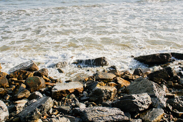Fototapeta na wymiar The windy waves hit the rocks by the sea.