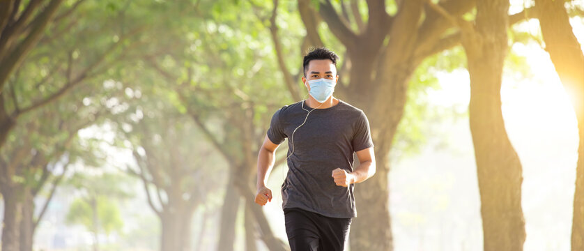  young man in face mask and running in the park