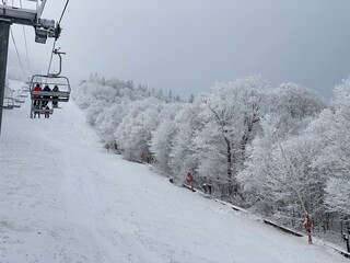 People on the ski lift chair going up at snowing winter day in VT