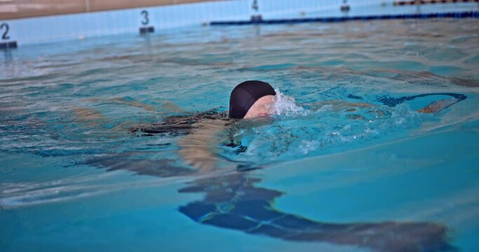 Older woman swimming in indoor pool