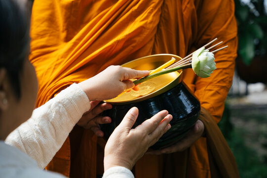 People giving alms offering with lotus and incense to monk in the morning.