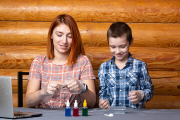The boy and his mother, scientists pour a mixture from a test tube into a container with chemical...