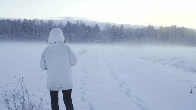 Woman taking pictures in fogy field at winter time.