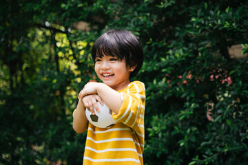 Cheerful boy holding football with smile on his face at park outdoors.