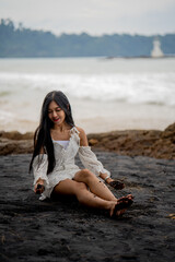 beautiful woman sitting on the black beach