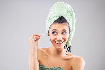 Beautiful young girl posing with towels after having a bath, holding cotton ear stick. Funny...