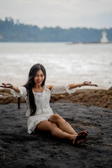 beautiful woman sitting on the black beach