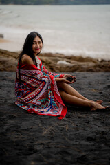 beautiful woman sitting on the black beach