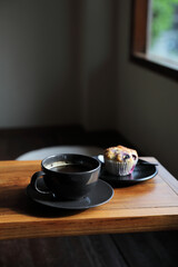 Coffee cup with muffin on wood table in local coffee shop