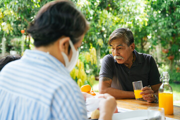 Grandfather enjoy orange juice in picnic place together.