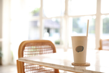 Iced coffee with paper glass in coffee shop background