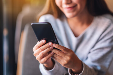 Closeup image of a beautiful young asian woman holding and using mobile phone