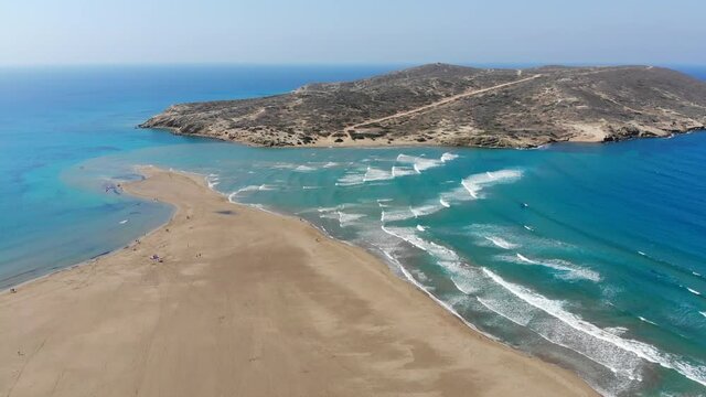 Scenic drone footage of Prasonisi peninsula in Rhodes in Greece surrounded by turquoise water. Kitesurfing. Waves on the Aegean Sea and calm flat water on the Mediterranean Sea.