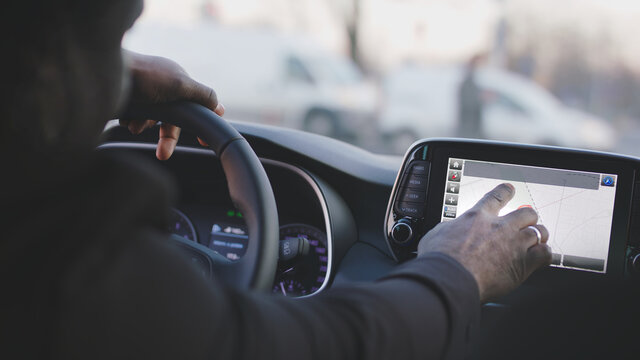 Close up of black man hand typing on the tablet in an electric car. High quality photo