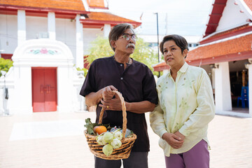 Portrait of asian senior elderly old couple make a merit in a temple.