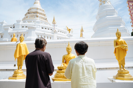 Asian Senior Elderly Old Couple Pay Respect To Buddha Statue In Thai Temple.