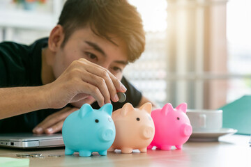 Obraz na płótnie Canvas A Man hand putting money coin into piggy for saving money wealth and financial concept.