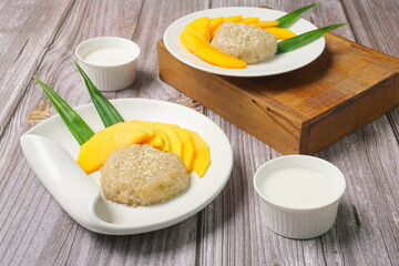 Mango Sticky Rice with coconut milk as sweet dessert from Thailand in wooden background 