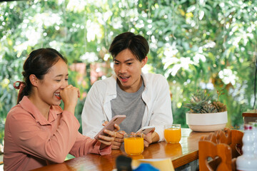 Young asian couple using smartphone to see something on social media.