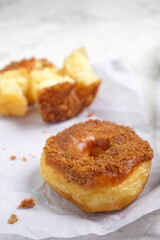 Donat or Donut or Doughnut as circle with hole sweet bread topped with caramel and biscuit crumbs. Selective focus, white shiny background