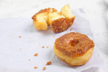 Donat or Donut or Doughnut as circle with hole sweet bread topped with caramel and biscuit crumbs. Selective focus, white shiny background
