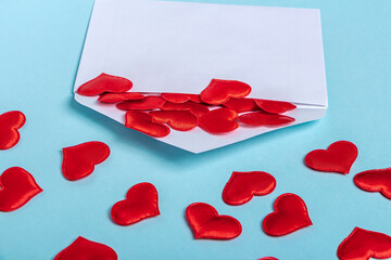 Valentines Day layout. Red hearts pours out of envelope on blue background. Template blank greeting card and envelope to wedding.  Flat lay, copy space for text